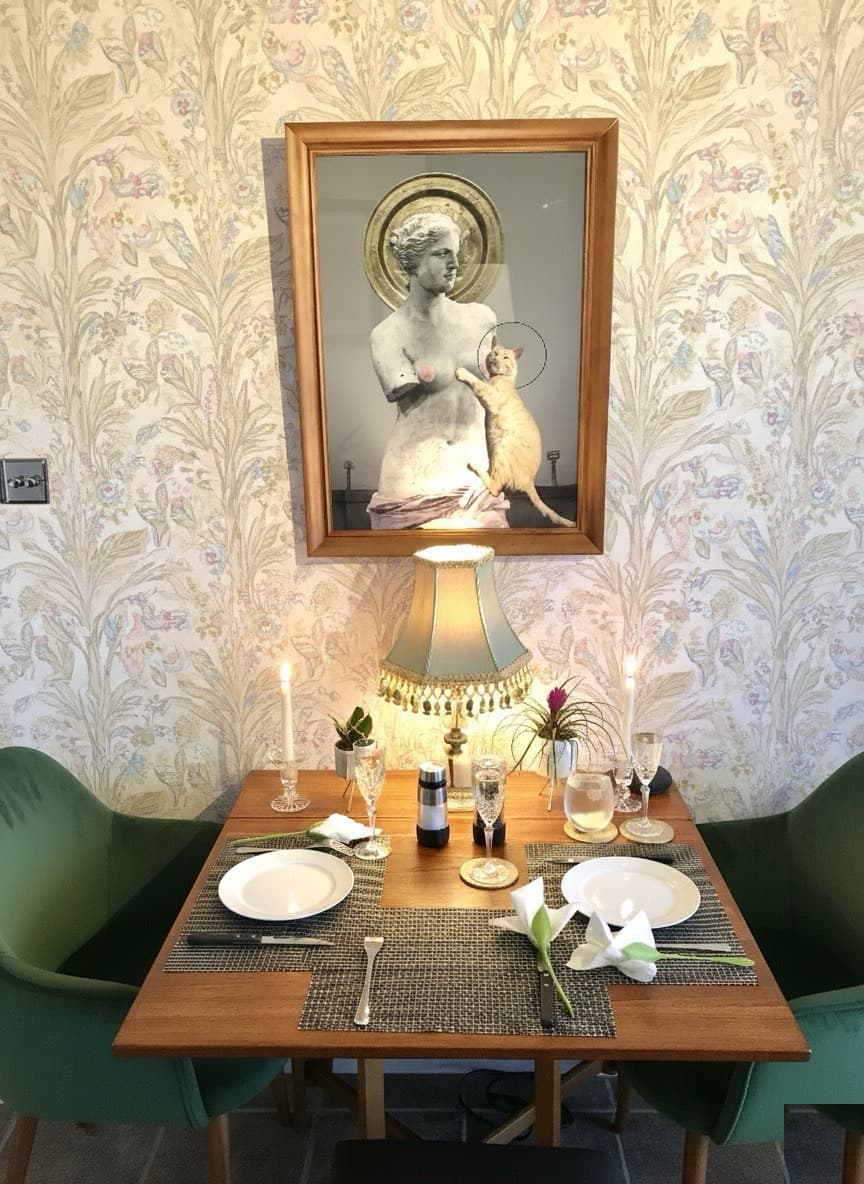 Dining nook with green chairs, Venus art, and botanical wallpaper